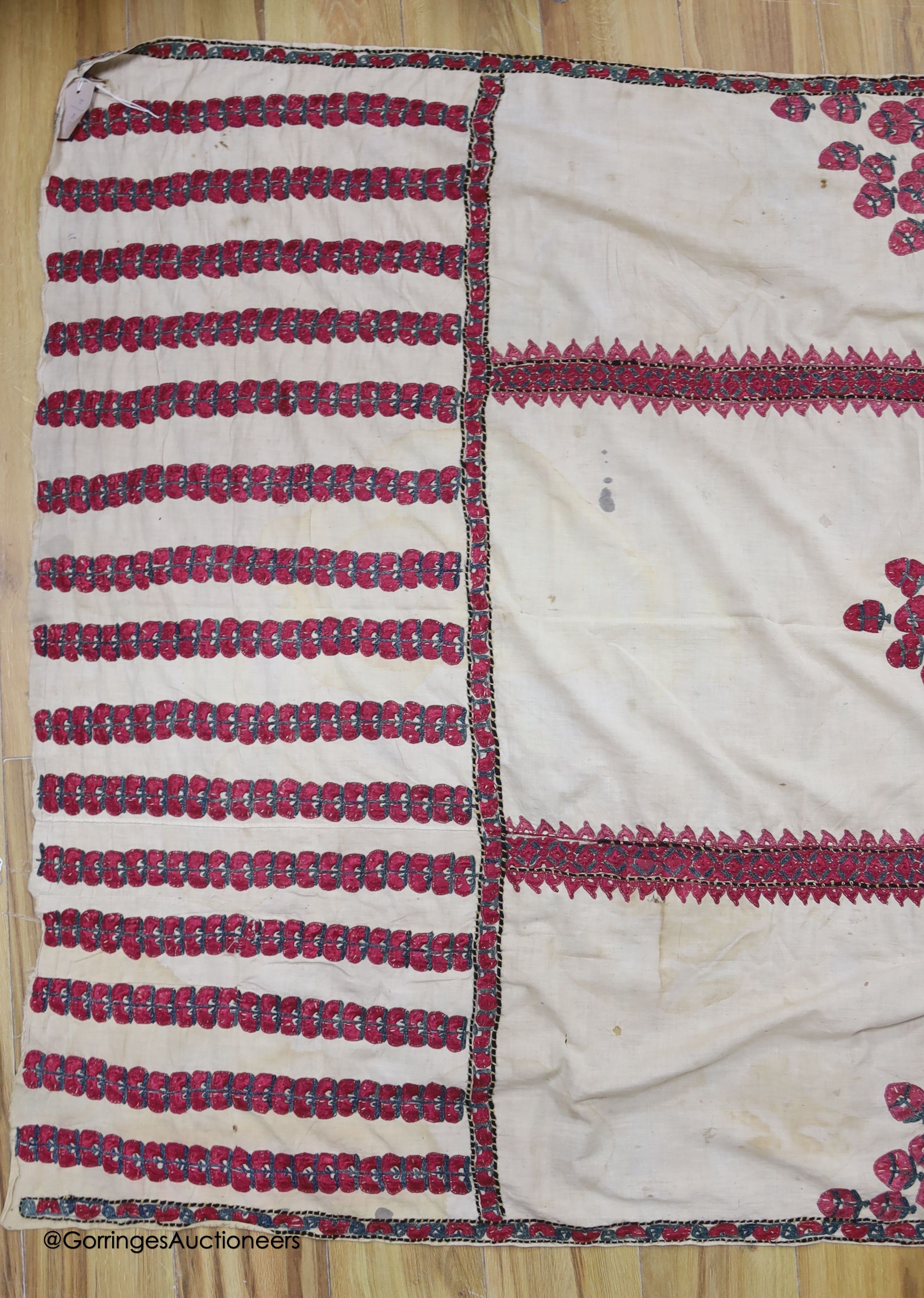 A silk embroidered Suzani, embroidered with cherry red flower heads with green stems and leaves in fine silk, width 134cm length 220cm